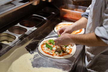 Pizza making process. Male chef hands making authentic pizza in the pizzeria kitchen.