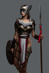 Portrait of amazon from past dressed in light armor and helmet holding spear and shield.