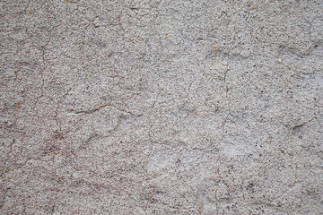 An old concrete wall with remnants of gray paint crumbling from time. Texture of eroded concrete.