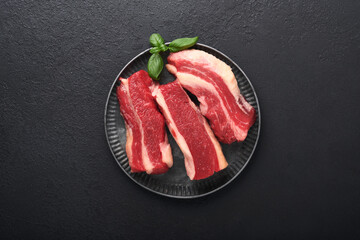 Steak beef. Raw steak New York with rosemary and spices on old iron plate on old dark stone background. Top view. Mock up.