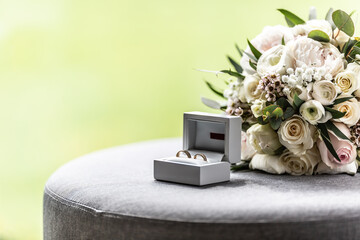 Open box with wedding rings placed next to a bouquette during a wedding - obrazy, fototapety, plakaty