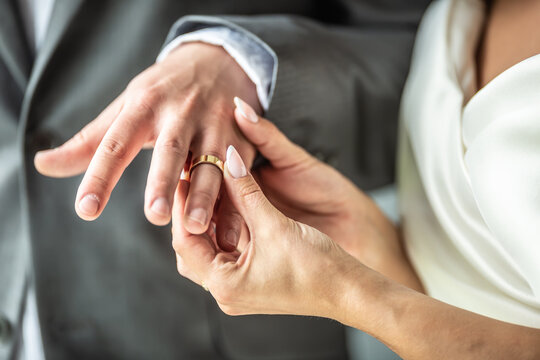 Detail of a bride putting a ring on a finger of a groom during a wedding ceremony