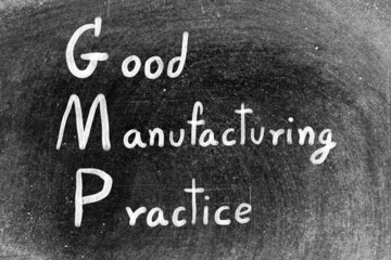 White hand writing in word GMP good manufacturing practice on black board background