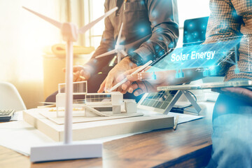 Selective focus. Architect team planning design apply renewable or solar energy on architectural building model with virtual reality technology hologram. Alternative green energy in future concept.