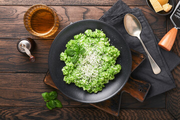 Italian risotto. Delicious risotto with pesto sauce or wild garlic pesto, basil, parmesan cheese and glass of white wine on old wooden table background. Italian dinner. Top view with copy space.