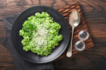 Italian risotto. Delicious risotto with pesto sauce or wild garlic pesto, basil, parmesan cheese and glass of white wine on old wooden table background. Italian dinner. Top view with copy space.