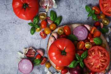 Flat lay composition of different tomatoes, onion, basil and garlic	