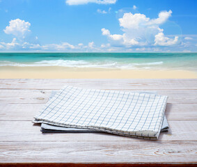Kitchen towel, napkin on wooden desk. Top view mockup. Summer sea beatch background.