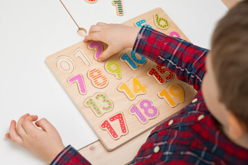 Kid learning numbers through game. Activity with wooden numbers. Educations at home, pre-school education, Montessori methodology. Toy to learn counting and stimulate imagination, creativity