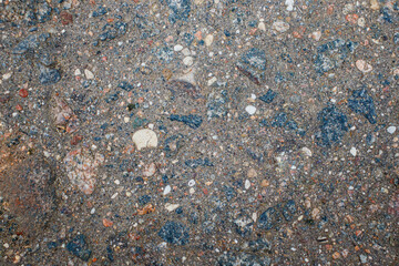 Texture of old hackneyed asphalt. Exposed bluish pebbles peeking out of the thickness of the asphalt.