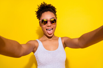 Photo of excited positive person make selfie showing tongue out protrude isolated on yellow color...