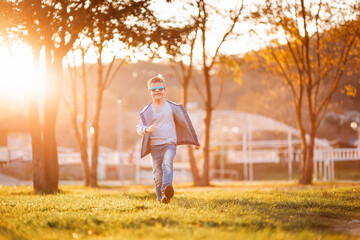 Smiling boy is funny walking through the autumn park. Copy space. Concept of childhood and adoption