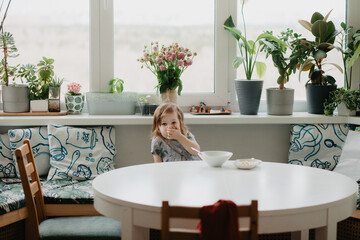 a little girl is sitting at the kitchen table eating soup
