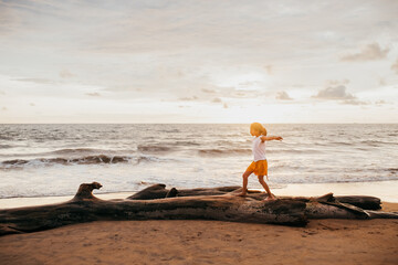 A little girl walking on a tree trunk at the beach
