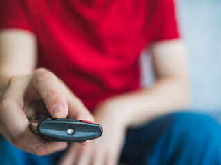 Man changing the channel on the TV. Unrecognizable man sitting at home with remote control watching tv sporting events