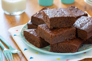 Plate of Homemade Chocolate Brownies with Cups of Milk on Kitchen Table
