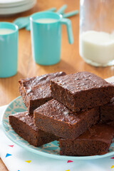Plate of Homemade Chocolate Brownies with Cups of Milk on Kitchen Table