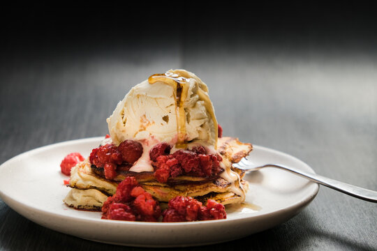 Close up of pancake stack with berries and ice cream.