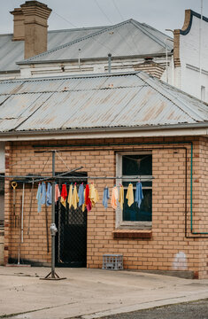 Colourful towels hung on hills hoist washing line outside a brick house
