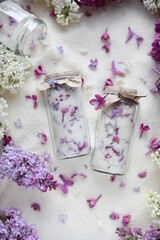 Obraz na płótnie Canvas Sugar with lilacs in small glass jars on scattered sugar. Edible flowers in cooking and confectionery. Seasonal spring preparations. Lilacs of different varieties.