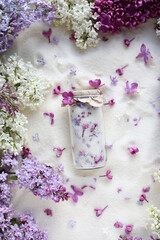 Sugar with lilacs in small glass jars on scattered sugar. Edible flowers in cooking and confectionery. Seasonal spring preparations. Lilacs of different varieties.