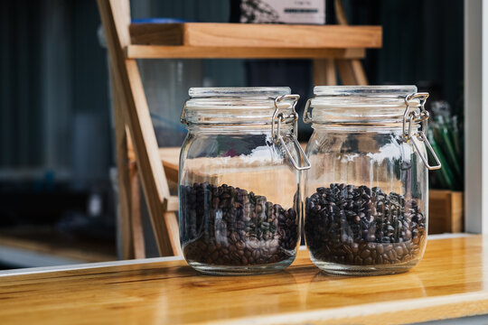Glass jar containing roasted coffee beans,Roasted coffee beans are packed in glass jars to maintain quality.     