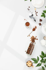 Coffee composition on light grey background, window shadow and green branches, flat lay, top view