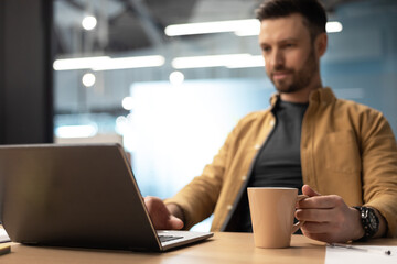 Businessman Using Laptop Drinking Coffee Working Online In Office