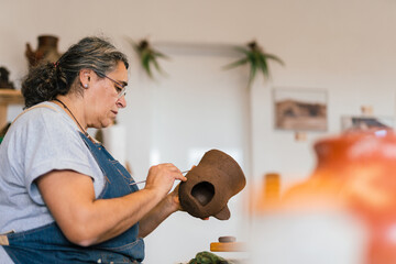 Craftswoman artisan creating pattern on ceramic pot