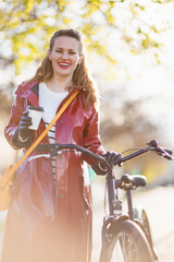 happy modern woman in red rain coat walking outside in city