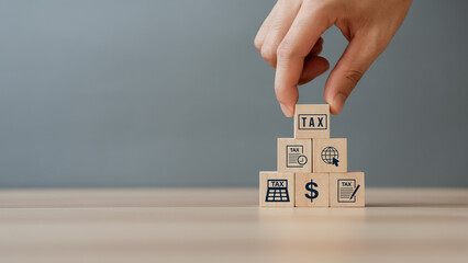 Hand putting tax icon in the wooden cube for income tax return and submit tax for payment tax documents online to the government