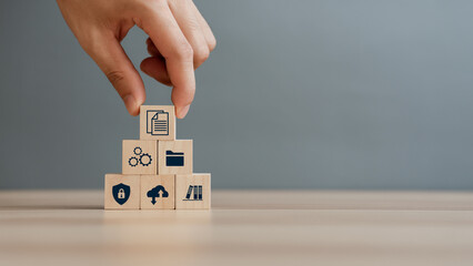 Hand putting document icon in the wooden cube for document management digital file data online records keeping, database technology, file access, and doc sharing.