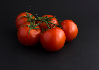 Closeup on red tomato on the black background. Copy space.
