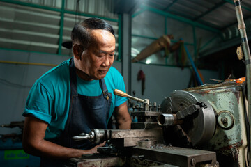 Portrait of Senior Asian man is a mechanic who owns a family business lathe. A small industrial lathe is being installed and initialized