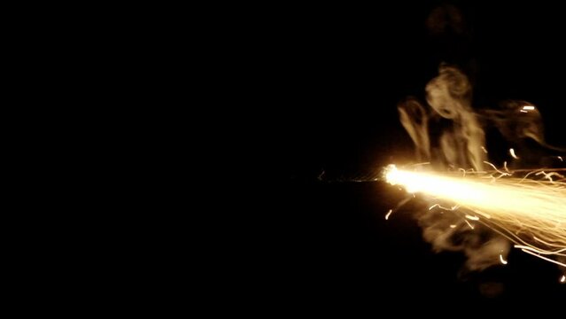 A professional fuse used to ignite bengal fires or bombs, lit with a lighter, burning in slow motion in the darkness. Begin of a long-lasting shot.
