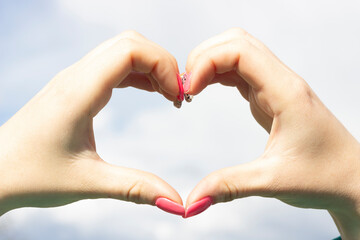 Women's hands in the form of a heart against the sky. Hands in the shape of a heart of love