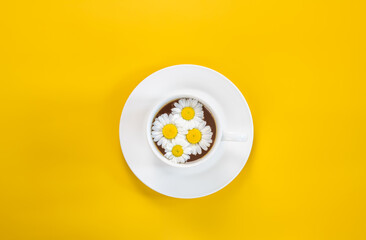 Cup of fresh healthy herbal chamomile tea on a yellow background 