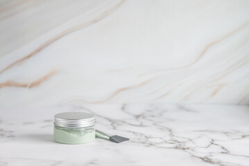 Clay facial mask in a jar on a light marble background with copy space for text. Face and body skin care. Natural cosmetics for cosmetic procedures. Beauty concept. 