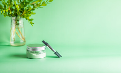 Green tea mask in a jar for face and body on a green background