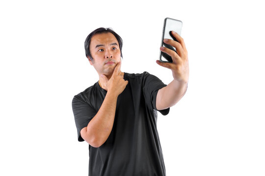 Asian man wore glasses and wear black t-shirts. Using mobile To take a picture  or selfie of himself isolated on blue background.