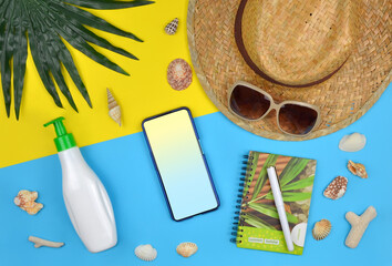Summer , vacation near the sea concept.  smartphone mockup with a blank screen and summer vacation accessories on yellow-blue background. top view