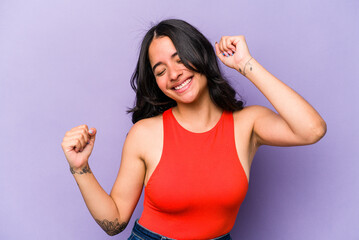 Young hispanic woman isolated on purple background dancing and having fun.