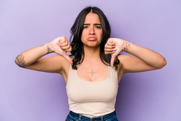 Young hispanic woman isolated on purple background showing a dislike gesture, thumbs down. Disagreement concept.