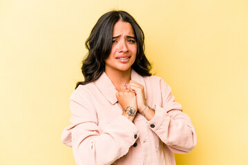 Young hispanic woman isolated on yellow background scared and afraid.