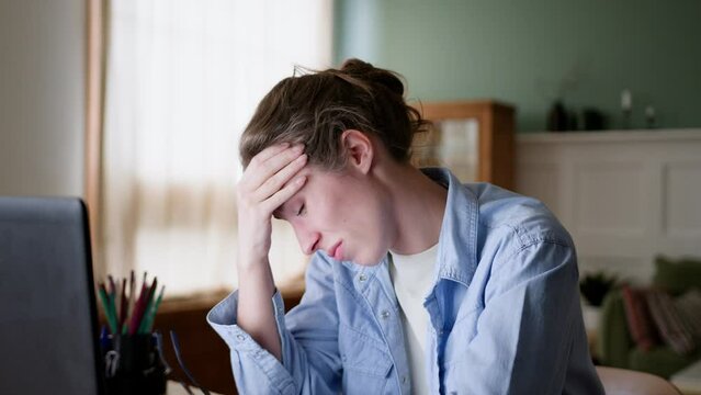 young upset woman with wet eyes looks on laptop screen, feels disappointed and tired caused failure. breathes out, puts on eyeglasses and tries again, starts typing on keyboard resolution.