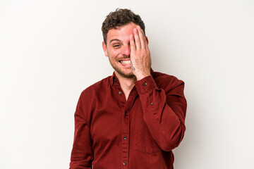 Young caucasian man isolated on white background having fun covering half of face with palm.