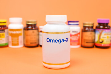 Dietary supplements omega-3 in a white jar and other jars on an orange background