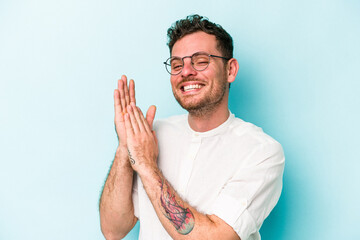 Young caucasian man isolated on blue background feeling energetic and comfortable, rubbing hands...