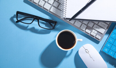 Computer keyboard, eyeglasses, mouse, notepad, pen, coffee.