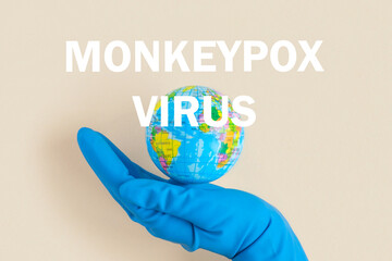 Phrase MONKEYPOX VIRUS written on paper with Earth globe. Beige pastel background. Top view, flat lay, copy space. Planet Earth model. World Medical and health concept